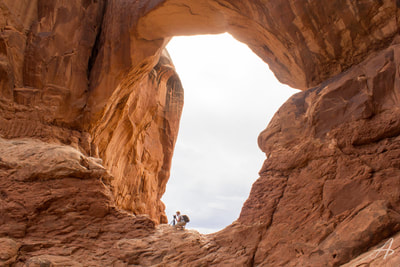 Parker crouches in one of the arches of Double Arch in Arches National Park